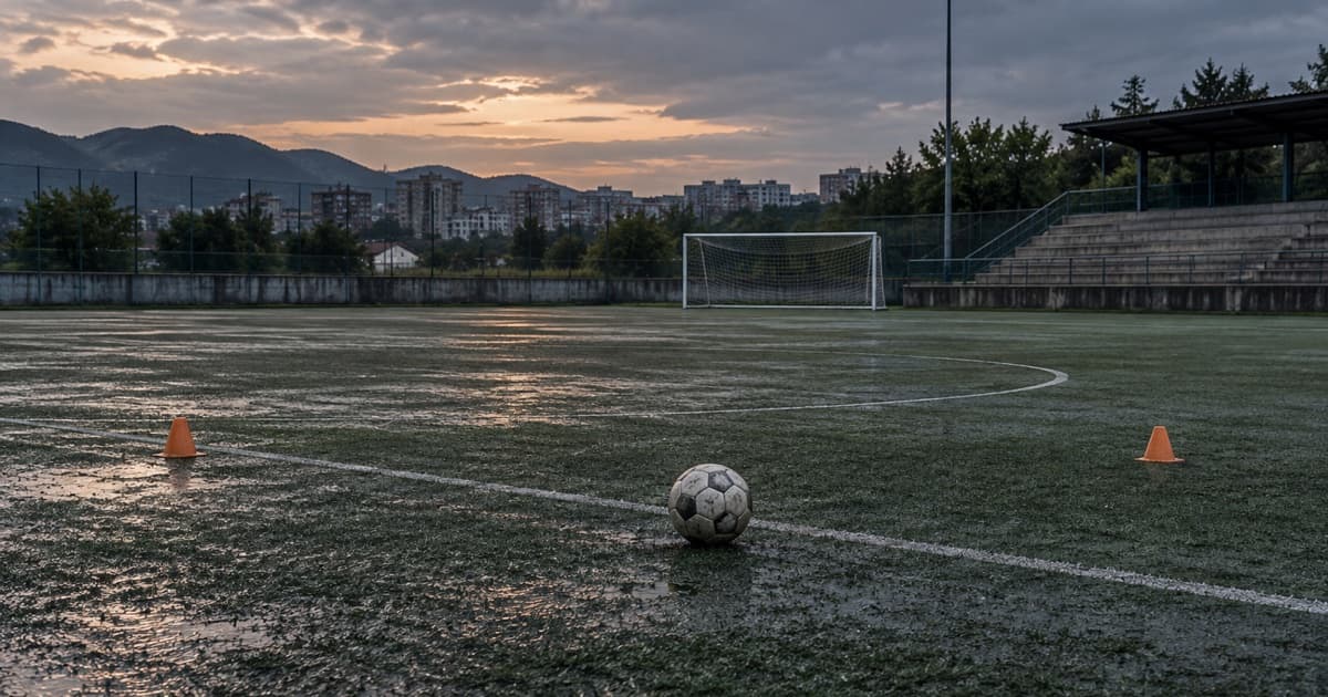 비에 젖은 빈 축구장에 놓인 공과 양쪽의 주황색 훈련 콘