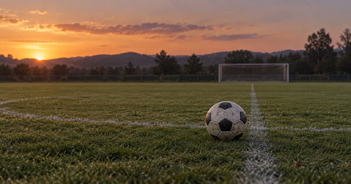 해질녘 빈 축구장 중앙선 근처에 놓인 축구공과 멀리 보이는 골대